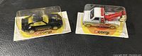 Both the yellow Porsche and white/red wrecker service truck die-cast models sealed on original display cards with Corgi branding