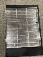 Top view of black framed display case with clear divided cover showing 33 compartments, scratches, and lock.