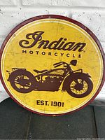 Front view of metal Indian Motorcycle sign showing yellow background, motorcycle graphic, and text