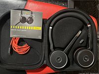 Jabra Evolve 75 headset with boom mic, USB charging cable, and quick start guide inside the black protective case with padded compartments.