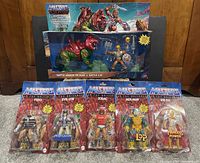 Front display of Battle Armor He-Man and Battle Cat boxed set with five blister-packed Masters of the Universe figures (Fisto, Evil-Lyn, Zodac, Mer-Man, She-Ra) laid out in front.
