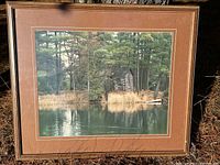 Full view of the framed Bob Graham photograph showing lake and cabin scene surrounded by forest trees with brown double-mat and wooden frame.
