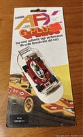 Vintage red and white Aurora AFX G-Plus 1734 Ferrari F1 slot car mounted on original product card showing front view and packaging details.