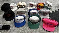 Overall group shot of 13 vintage fishing trucker hats in various colors and advertising designs.