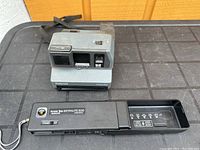 Polaroid Impulse camera and Kodak Tele-Ektralite 600 camera on table