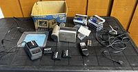 Full lot layout showing camcorder, batteries, charger, tapes, cables, remote, original box, and documentation on black table.