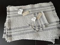 Set of 4 hand-woven placemats and 4 coasters displayed with tags visible, textures and fringe edges shown.
