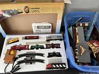 Original packaging and styrofoam tray holding train engines, railcars, curved track pieces, and power controller.