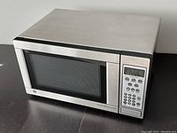 Front angle photo showing the stainless steel exterior with black framed door and mesh screen window.