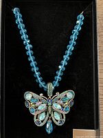 Blue glass bead butterfly necklace in black display box, showing full necklace and pendant shape.