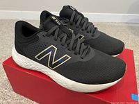Side angle view of new New Balance M520MB7 black running shoes on top of original red box.