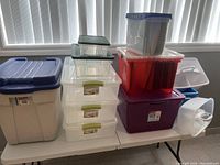 Photo showing various plastic bins and containers stacked on a table near window light.
