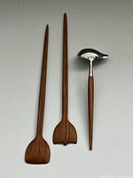 Front view of two teak wooden salad servers and one metal spoon with wooden handle