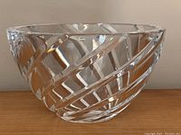 Side view of heavy crystal bowl showing swirling raised diagonal cut bands on clear crystal surface. Shows partial Orrefors label near rim.