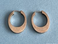 Pair of vintage sterling silver hoop earrings shown from front angle on blue background.