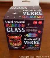 Photo of original packaging box for liquid activated blinking glass, displaying text about the product's features like multicolor blinking, 7oz capacity, perfect for parties.