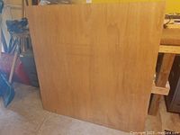 Photo showing one marine grade plywood sheet with smooth natural wood grain surface, standing against a wall in a workshop environment.