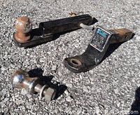 Two metal hitch ball carriers with one having CURT brand label, 1 pin and clip nearby, two 1 7/8 inch hitch balls shown, one attached to carrier and one separate with mounting bolt