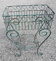 Top and side views of the green metal two level plant stand showing the scroll details on the baskets and legs.