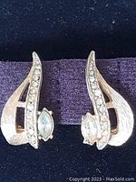 Front view of both earrings showing design, metal texture, rhinestones including missing stone.