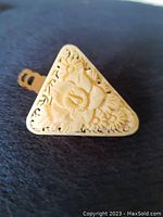 Front view of triangular carved floral celluloid scarf clip with pierced detailing and rose motif