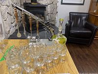 Overview photo showing multiple shot glasses and wine glasses in front, retro bar tools hanging behind, and decanter with stopper on table