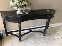 Black Bombay Company hall table with curved front and gold accents on leg joints, no drawer.