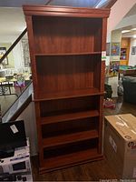 Front view of tall, dark wood laminate bookcase with three shelves, showing overall condition and structure.