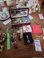 Jewelry box open showing assortment of bracelets, necklaces, and watches on table
