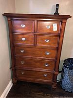 Front view of tall wooden dresser showing six drawers and silver metal handles with visible wear.