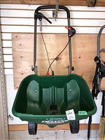 Front view of green Scotts Deluxe EdgeGuard broadcast spreader with handle and hopper, showing overall structure and wear.