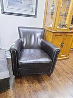 Full view of the dark brown leather club chair with nailhead trim showing general condition and shape.
