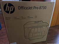 Front view of the HP OfficeJet Pro 8730 box showing product name and printed image of the printer, emphasizing wireless print, fax, scan and copy features.