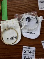 Two Pandora bracelets, one gold-toned and one silver-toned, each with Pandora branded pouch