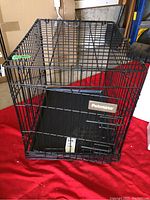 Front and top view of black metal PetMate pet cage with plastic base and single door.