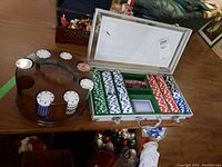 Poker chip set in aluminum carrying case with chips in assorted colors, two decks of cards, and dice, accompanied by wooden chip stand with chips stacked.
