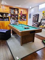 Full perspective view of Cooper pool table set up in a room with accessories on top and furniture around