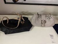 Pair of purses: black Michael Kors leather purse and white Guess purse with decorative straps and clasp