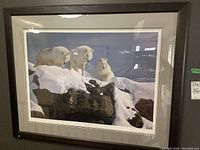 Framed print featuring three white wolves on snow-covered rocks under a dark sky, showcasing the artwork and frame condition.