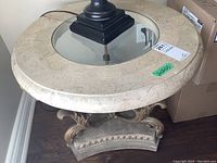 Top view showing round stone composite table top with central beveled glass insert and part of lamp on top.