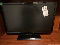 Front view of Insignia 24-inch LED TV with black screen and stand, showing label sticker on screen.