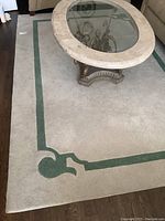 Rug under glass coffee table showing green border and beige base