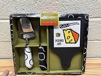 Cheese serving set including cheese slicer, bottle opener, and serving board in packaging.