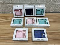Photo of 8 Airpod cases in original boxes in various colors including pink, blue, teal, and navy.