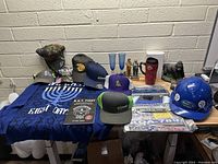 Photo showing the entire assortment of hats, figurines, apparel, helmet, and signage arranged on a table.