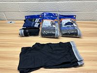 Packaged sets and individual boxer briefs laid out on table, showing multiple color patterns and brand Gildan waistband.