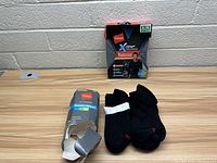 Photo showing the Hanes men's thermal shirt packaging and several pairs of black Hanes socks on a table.