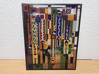 Front view of the glass suncatcher showing the colorful geometric pattern and thin black frame.