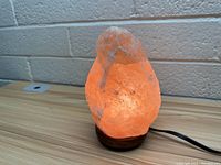Illuminated pink Himalayan salt lamp showing warm glow and natural salt texture.