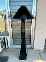 Full view of the tall black floor lamp with square base and wide conical shade.
